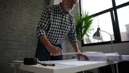 Wall Mural - Mature architect or engineer open blueprint on the desk in office. Architect working in office