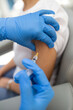 © Austockphoto - Close up of shot a healthcare worker with blue gloves giving a shot to a woman