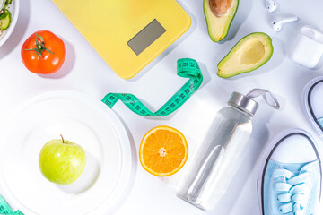 Spring slim and fitness, active living concept. Small yellow dumbbells, bottle of water, sports shoes, scales, salad, fresh vegetables and fruits on a light white background, top view copy space