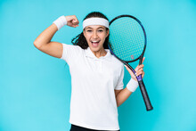 Young Woman Isolated On Blue Background Playing Tennis And Celebrating A Victory