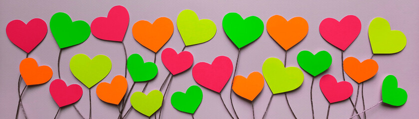 banner with colorful valentines cut out of paper. top view. colored hearts on thread stalks on light