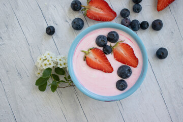 Wall Mural - Yogurt, strawberries, blueberries on a light background