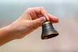 A small bell in the girl's hand on a neutral background, close-up,