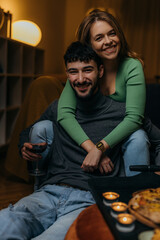 Wall Mural - Woman hugging her loving boyfriend from behind. they are looking at camera