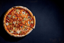 Appetizing Pizza With Hunting Sausages, Mozzarella Cheese, Pickled Cucumbers, Chili Peppers On A Tomato Base On Black Background