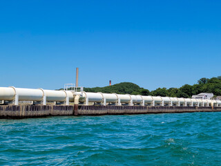 white industrial pipeline on lake michigan with bright blue sky