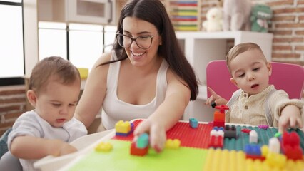 Poster - Teacher with boys playing with construction blocks sitting on table at kindergarten