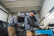 © PoppyPix - Skilled car mechanic repairing a car using computer diagnostic modern technology. High-quality photo