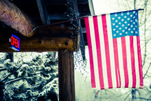 Open Sign On Front Of Snowy Lodge With American Flag Hanging In Small Alaska Ski Town.