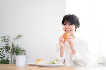 Wall Mural - Asian woman eating bread A fresh breakfast scene with a beautiful morning sunrise