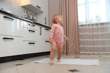 Wall Mural - Cute baby learning to walk in kitchen near window