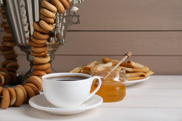 Wall Mural - Metal samovar with cup of tea and treats on white wooden table, space for text