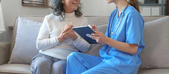 Portrait of attractive young caucasian female nurse elderly caregivers with senior patient home caring for elderly asia female patients on couch, indoors.