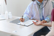© NanSan - Female elder doctor takes a history of a patient and gives a consultation about osteopathy to a female patient after measuring blood pressure and heart rate and encouragement by holding hands