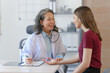 © NanSan - Female elder doctor takes a history of a patient and gives a consultation about osteopathy to a female patient after measuring blood pressure and heart rate and encouragement by holding hands