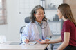 © NanSan - Female elder doctor takes a history of a patient and gives a consultation about osteopathy to a female patient after measuring blood pressure and heart rate and encouragement by holding hands