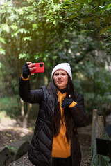 Wall Mural - Latin woman making videos with her phone in the forest