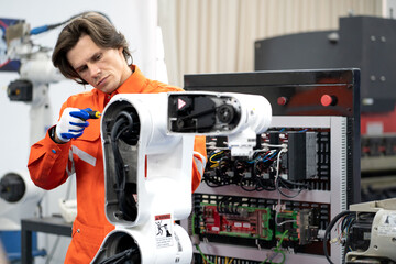 Computer science development engineer working on robotic arm connection and control at electronic futuristic technology center. Modern people training in industry 4.0 automated engineering workshop