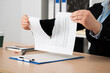 © cunaplus - Close-up of the hands of a businesswoman tearing up the signed contract document sitting at a desk in the office