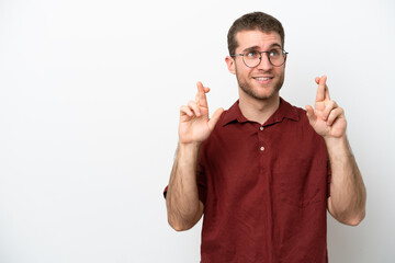 Wall Mural - Young caucasian man isolated on white background with fingers crossing and wishing the best