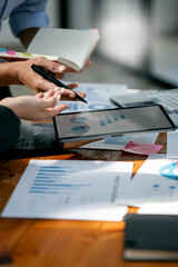 Wall Mural - Two confident business people point to graphs and charts on tablet to analyze data, balance sheet, account and net profit