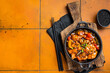Chinese Sweet and sour chicken with colorful bell pepper in a skillet. Orange background. Top view. Copy space