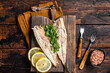 Delicious baked mackerel fillets with greens, garlic and lemon on wooden board. Wooden background. Top view