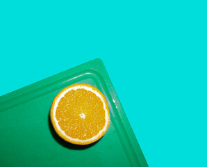 Sliced orange on a green board. Blue background.