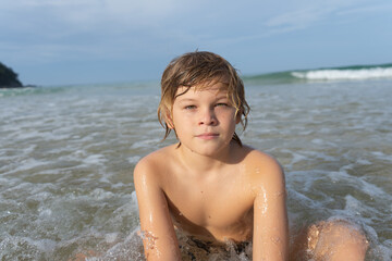 the child sits in the sea on the beach