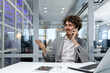 © Liubomir - Successful successful businessman talking cheerfully in office on phone, hispanic financier working at workplace using laptop, man in business suit at work happy with achievement.