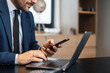 © ivanko80 - Businessman typing on laptop computer and using smart phone