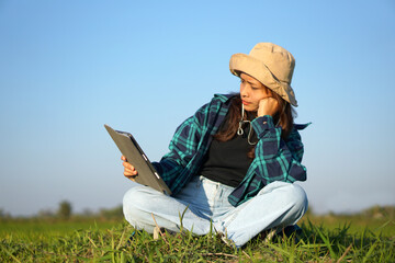 Asian female farmer uses computer to analyze rice growth.