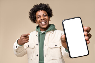 Happy African American teen student holding mobile cell phone pointing finger at smartphone mock up big screen template presenting application, using cellphone showing ad isolated on beige background.