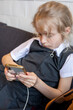 © Nataliia Makarovska - little schoolgirl girl playing smartphone while waiting for parents
