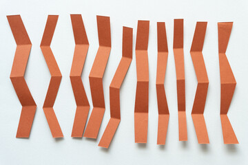 Wall Mural - folded brown paper stripes with slightly chevron edges arranged vertically on blank paper