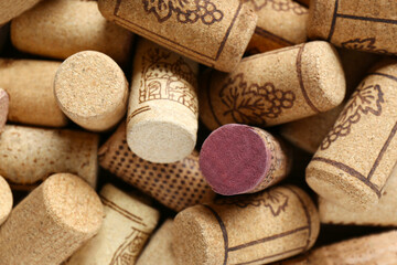 Many corks of wine bottles with grape images as background, top view