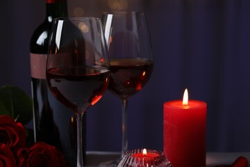 Wall Mural - Glasses of red wine, rose flowers and burning candles against blurred background. Romantic atmosphere