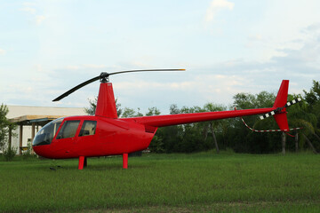 Wall Mural - Modern red helicopter on green grass outdoors