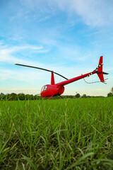 Wall Mural - Modern red helicopter on green grass outdoors, low angle view