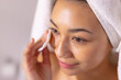 © Wavebreak Media - Close up of happy biracial woman wearing towel cleansing face in bathroom