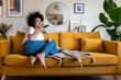 Happy African American woman sending voice note message using mobile phone at home sitting on couch. Copy space.