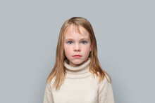 Portrait Of Serious Funny Little Girl Looking At Camera On Grey Background