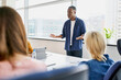 © baranq - African businessman pitching new business ideas to group of coworkers