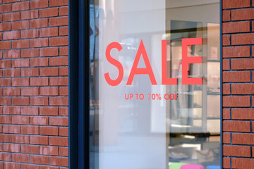 Close-up of a store window with a sale sign.