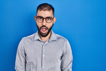 Canvas Print - Middle east man with beard standing over blue background afraid and shocked with surprise expression, fear and excited face.