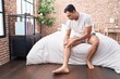 © Krakenimages.com - Young hispanic man suffering for knee injury sitting on bed at bedroom