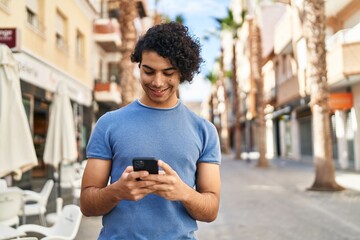 Sticker - Young hispanic man smiling confident using smartphone at street