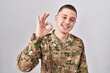 © Krakenimages.com - Young man wearing camouflage army uniform smiling positive doing ok sign with hand and fingers. successful expression.