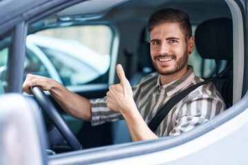 Poster - Hispanic man with beard driving car smiling happy and positive, thumb up doing excellent and approval sign