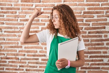 Sticker - Young caucasian woman holding art notebook strong person showing arm muscle, confident and proud of power